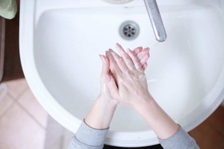Woman washing hands over sink to stay healthy when traveling