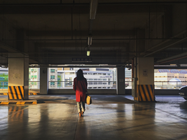Woman walking alone in dark airport parking ramp.