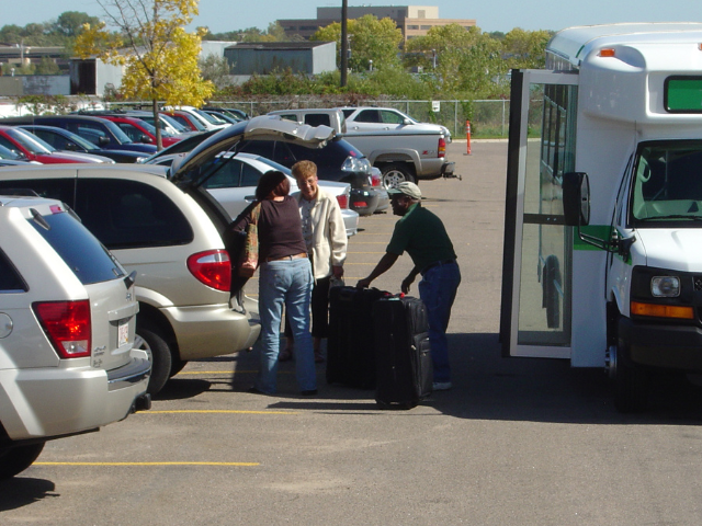 People loading luggage into an airport shuttle bus.