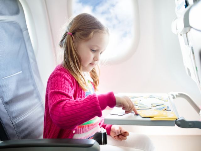 Young girl playing with a puzzle on an airplane.