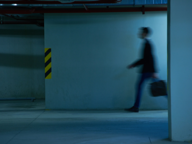 Shadow of a person walking in a dark parking garage.